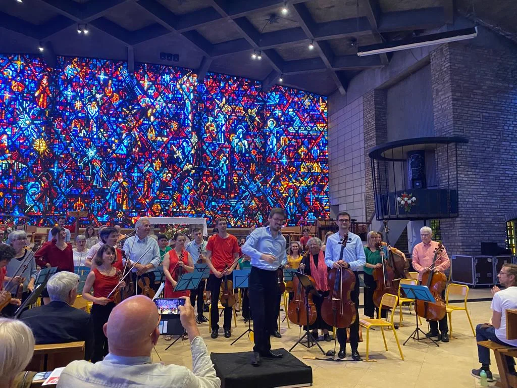 L'orchestre debout et vitraux en fond